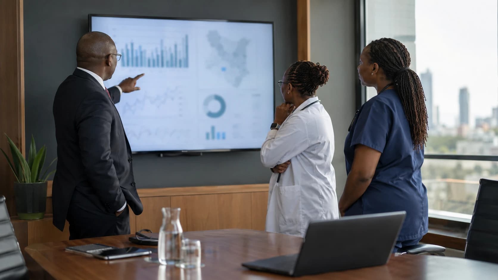 A hospital administrator and clinicians reviewing charts on a boardroom screen